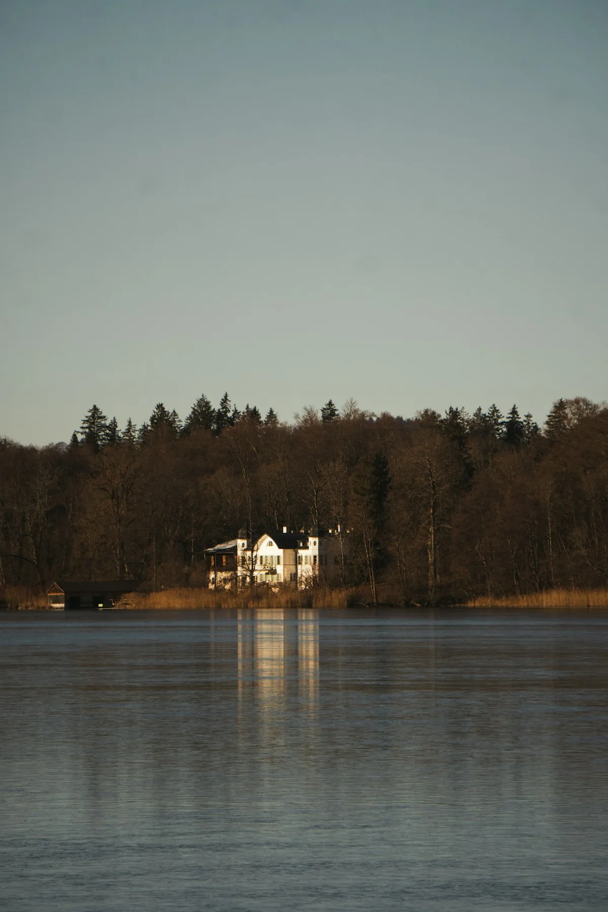 A lakefront estate seen from across the water at dusk